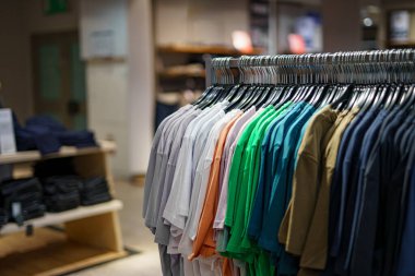 Alışveriş merkezindeki bir giyim mağazasında askıdaki erkek tişörtleri..