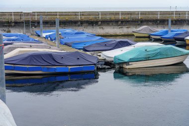 Boats and yachts are covered and prepared for winter on the dock in a private port. clipart