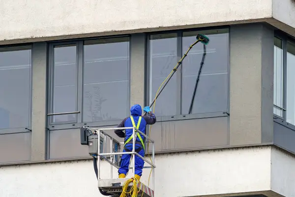 Bir işçi çok katlı bir binanın camlarını siler..