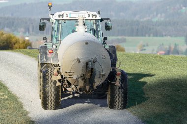 Tarım alanında gübreleme ve sulama için tankı olan bir traktör..