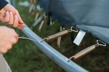 Adamın biri trambolinden yayları sökerken çıkartıyor..
