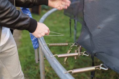 Adamın biri trambolinden yayları sökerken çıkartıyor..