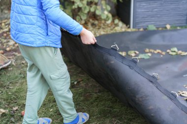 Çocuklar evde büyük bir trambolini parçalara ayırıp tekrar birleştiriyorlar..