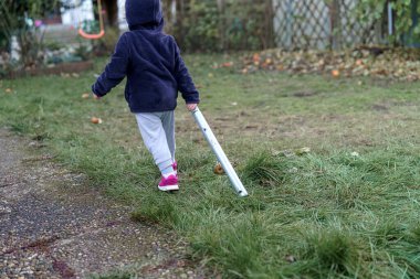Çocuklar parçalanmış trambolin çerçevesini depolamak için taşırlar..