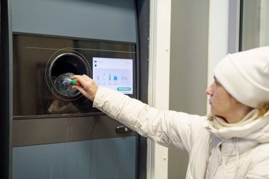 Bir kadın plastik şişeleri plastik geri dönüşüm makinesine geri gönderir..