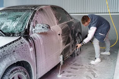 Şoför arabayı fırça ve şampuanla yıkar..