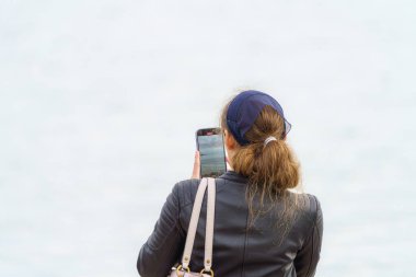 Bir kız akıllı telefonuyla seyahat ederken manzara fotoğrafları çekiyor..