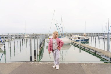 Küçük bir kız yatların arka planında poz veriyor..