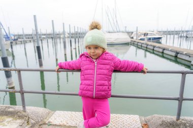 Küçük bir kız yatların arka planında poz veriyor..