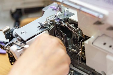 Bir kadın terzi dikiş makinesini temizler ve yağlar..