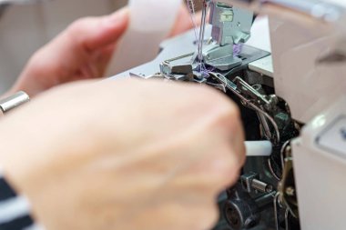 Bir kadın terzi dikiş makinesini temizler ve yağlar..