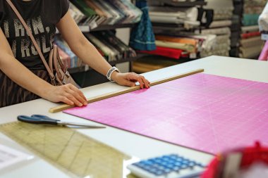 Bir kadın, fabrikada dikiş deseninin yanında elinde makas tutar..