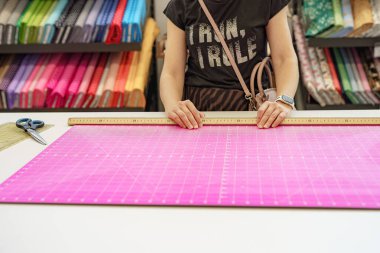 Bir kadın, fabrikada dikiş deseninin yanında elinde makas tutar..