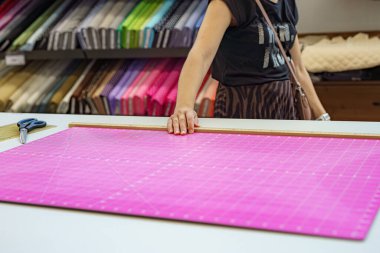 Bir kadın, fabrikada dikiş deseninin yanında elinde makas tutar..