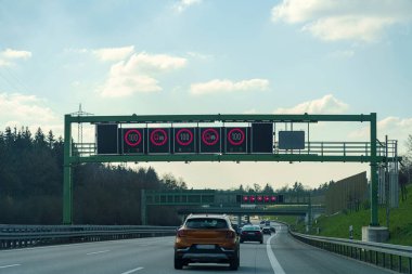 Parlak elektronik yol işaretleri otoyolda seyahat eden araçlar için hız limitlerini gösteriyor. Açık hava ve minimum trafik öğleden sonra sakin bir sürüş ortamı yaratır.