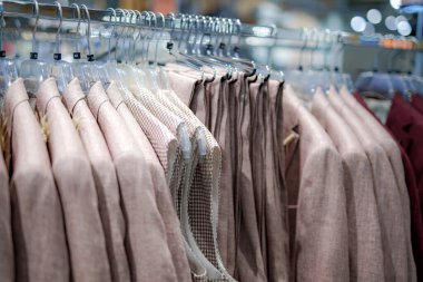 Çağdaş bir butikte, yumuşak nötr tonlarda çeşitli özel dikim ceketler sergilenmektedir. Müşteriler öğleden sonra ışığında şık seçenekleri gözden geçirirler..