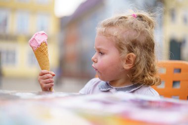Genç bir kız canlı bir masada otururken pembe bir dondurma külahının tadını çıkarırken hayat dolu bir gün başlıyor. Düşünceli bir şekilde bakar, yazın neşesini yakalar..