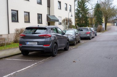 Soğuk bir kış günü, diğerleri kaldırımda kuyruk oluştururken, birkaç araba sakin bir yerleşim yeri caddesi boyunca park halindeyken, gri bir SUV belirlenmiş bir park yerini işgal ediyor..