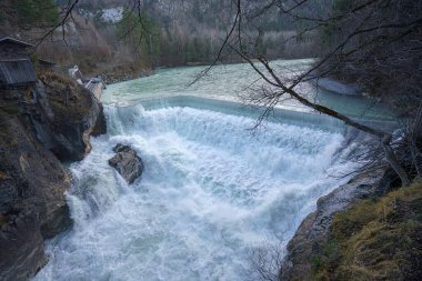 Nefes kesici bir şelale durgun bir turkuaz nehrine dökülür ve muhteşem bir manzara yaratır. Uçurumların ve ağaçların etrafındaki doğal güzellikleri artırır..
