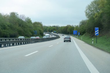 Araçlar yemyeşil otlaklarla kaplı iyi korunan bir otoyol boyunca seyahat ederler. Bulutlu gökyüzü, sürücüler sabah yolculuklarında yol alırken sakin bir atmosfer yaratıyor..
