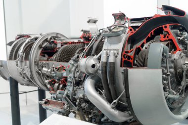 Ziyaretçiler, bir havacılık müzesindeki bir jet motorunun ayrıntılı kesitine hayran. Sergide modern havacılık mühendisliğinin gelişmiş teknolojisi ve mekanik bileşenleri vurgulanıyor.