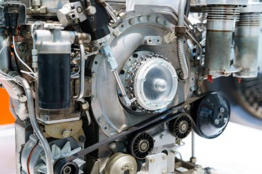 Modern bir otomotiv motoru, mekanik parçalarının, kemerlerinin ve sistemlerinin karmaşık detaylarını bir atölye ortamında sergiliyor. Mühendisler ve araba severler için ideal..