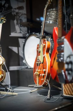Farklı tarzlarda gitarlar bir müzik müzesinde belirgin bir şekilde sergilenir. Kurulumda klasik bir akustik gitar, elektro gitarlar ve çekici bir ortam yaratan bir bateri seti yer alıyor..