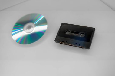 Ses teknolojisinin evrimini gösteren bir kaset ve kompakt disk pürüzsüz bir yüzey üzerinde yan yana görüntülenir..