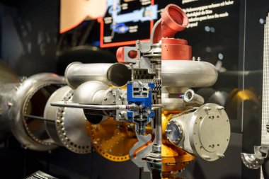 Bir uzay müzesinde belirgin bir şekilde sergilenen jet motoru modeli karmaşık bileşenleri ve modern tasarımı ön plana çıkarıyor. Ziyaretçiler havacılık teknolojisindeki gelişmeleri araştırıyorlar.