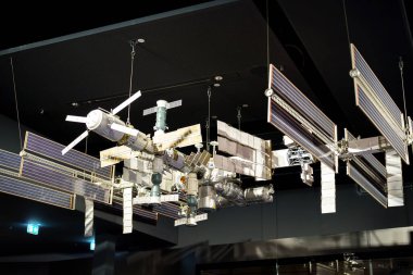 Uluslararası bir uzay istasyonunun ayrıntılı bir modeli sergi alanında askıya alındı. Karmaşık tasarım güneş panelleri ve çeşitli modülleri gösteriyor, ziyaretçilerin dikkatini çekiyor..