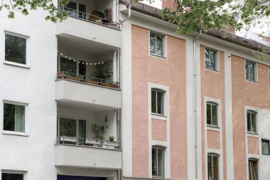 Bitkiler ve dekorasyonlarla süslenmiş balkonlar kentsel alandaki bir binaya karakter katıyor. Yapıda gür ağaçlarla çevrili dokulu duvarların bir karışımı yer alıyor..