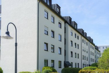 İyi korunmuş bir bölgede çağdaş bir apartman dairesi duruyor. Açık renkli dış görünüşü güneş ışığını yansıtırken, çevresindeki yeşillik davetkar atmosfere katkı sağlıyor..
