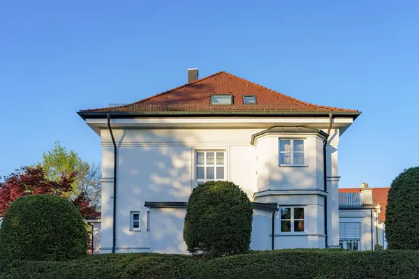 İyi bakımlı bir bahçenin ortasında, iki katlı çağdaş bir konut zarif bir mimari stil sergiliyor. Açık gökyüzü sakin banliyö atmosferini güçlendirir.