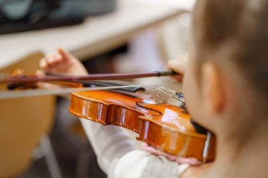 Bir çocuk müzik aletleriyle dolu iyi ışıklandırılmış bir sınıfta keman çalma pratiği yaparken dikkatle odaklanır. Ayarlar yaratıcılığı ve öğrenmeyi teşvik ediyor..