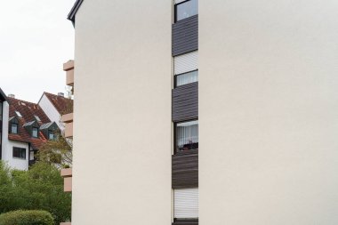 Pürüzsüz, modern bir bina açık renkli ve farklı pencereleri olan bir dış görünüme sahiptir. Yapıyı saran yemyeşil, şehir mimarisi ile bulutlu bir gökyüzüne karşı kurulmuş..