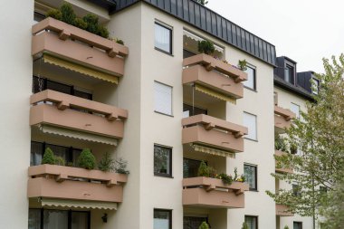 Çağdaş bir konut binasında çeşitli bitki ve çiçeklerle süslenmiş geniş balkonlar bulunur. Yapı sakin bir çevre ile sorunsuz bir şekilde harmanlanır ve kentsel yaşamı geliştirir..