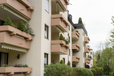 Çağdaş bir apartman dairesinin, saksı bitkileriyle süslenmiş balkonlarıyla ilgili bir sürü hikaye. Genel atmosfer bulutlu bir günde sakin ve davetkar bir şehir ortamı olduğunu gösteriyor..