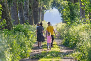 Dört çocuk, aydınlık bir yaz gününde ağaçlarla çevrili çimenli bir yolda birlikte yürürler. Güneşin sıcaklığından ve doğanın güzelliğinden zevk alırlar..