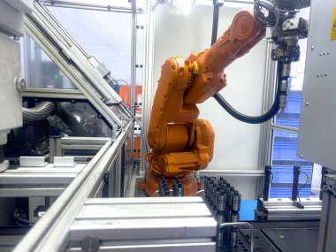 Çoklu eklemlerle donatılmış bir robotik kol makinelerle dolu çağdaş bir imalat ortamında kesin montaj görevleri yerine getirir.