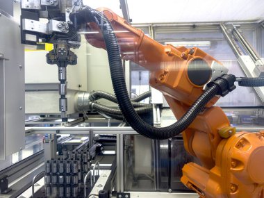 Bir robotik kol, temiz bir üretim ortamında aktif olarak montaj görevleriyle uğraşır ve gelişmiş otomasyon teknolojisinin iş başında olduğunu gösterir..