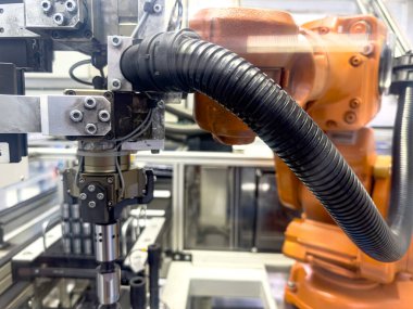 Hareketli bir fabrikada, özel aletlerle donatılmış bir robotik kol karmaşık montaj görevleriyle meşguldür. Hassasiyet ve verimlilik bu otomatik ortamı tanımlar.