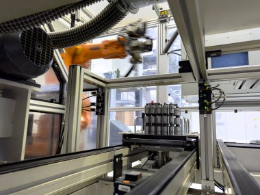 Robot silahlar ve makineler modern bir imalat fabrikasında birlikte çalışırlar, gündüz saatlerinde bileşenleri verimli bir şekilde bir üretim hattında birleştirirler..