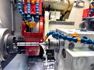 CNC makinesini iş başındayken yakın çekimde, soğutucu akarken metali kesen bir alet sergiliyor. Çevre, doğruluğa odaklanmış yüksek teknolojili bir imalat ortamını yansıtıyor.