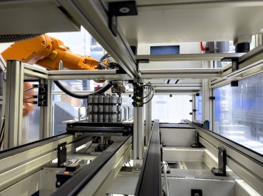 Gelişmiş teknoloji ve otomasyon sistemleri sergileyen bir robot kolu modern bir üretim tesisi içinde hassas operasyonlar gerçekleştiriyor. Çevre verimlilik için düzenlenmiştir..
