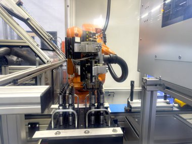 Turuncu dış görünüşlü bir robotik kol modern bir imalat ortamında ileri teknoloji ve otomasyon sergiliyor..