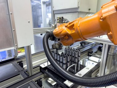 Robot bir kol, modern bir üretim tesisi içinde yüksek hassasiyetli bileşenlerin montajında kullanılıyor. Çevre verimlilik için otomatik sistemlerle yapılandırılmıştır..