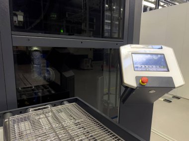 Üretim ortamında, bir endüstriyel makine için çeşitli ayarları ve seçenekleri gösteren bir kontrol paneli gösterilir. Tesiste üretimde kullanılan ileri teknoloji sergileniyor..