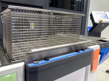 Ticari mutfak ortamındaki endüstriyel pişirme ünitesine metal bir sepet yerleştiriliyor. Ekipmanlar yüksek verimli gıda hazırlamak için tasarlandı..