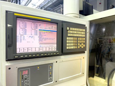 Bir CNC makine kontrol paneli, gündüz vardiyası sırasında modern bir endüstriyel atölyede çeşitli işletim parametrelerini ve ayarlarını aktif olarak gösteriyor.