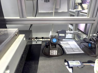 Temiz bir endüstriyel laboratuardaki bankta hassas ölçümler için çeşitli araçlar düzenlenir. Ekipmanlar kalite kontrol ve kalibrasyon süreçlerinde kullanılır..